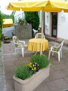 einen Tisch mit einem Sonnenschirm, 2 Stühlen und Blumen in der Unterkunft Villa Roder in Umkirch