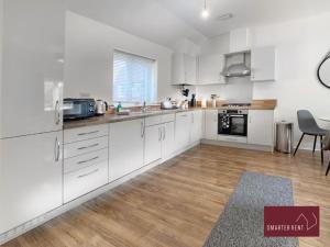 a kitchen with white cabinets and a wooden floor at Jennetts Park, Bracknell - 2 Bedroom Maisonette With Parking in Bracknell