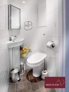 a white bathroom with a toilet and a sink at West End, Woking - 2 Bed House With Parking and Garden in Bisley