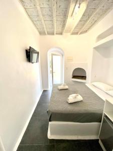 a white room with a bed and a tv at MYKONOS VIBES AIRPORT STUDIOS AND APARTMENTS in Aggelika