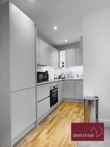 a kitchen with white cabinets and a wooden floor at Eton Windsor - 1 Bedroom Flat - With Parking in Eton