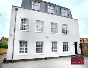 a white building with windows on a street at Eton, Windsor - 1 Bedroom First Floor Apartment - Parking in Eton