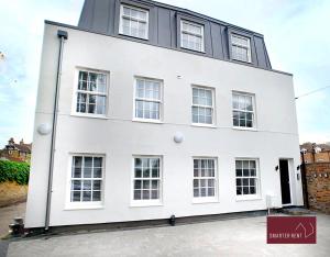 a white building with windows on a street at Eton Windsor - 1 Bedroom Flat - With Parking in Eton +3 photos