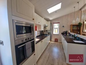 a large kitchen with wooden floors and white cabinets at Milford on Sea - 4 Bedroom Lodge in Shorefield Country Park in Milford on Sea +5 photos