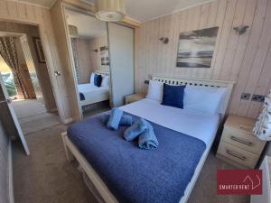 a bedroom with a large bed with a blue blanket at Milford on Sea - 4 Bedroom Lodge in Shorefield Country Park in Milford on Sea