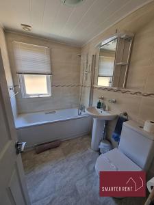 a bathroom with a bath tub and a sink at Milford on Sea - 4 Bedroom Lodge in Shorefield Country Park in Milford on Sea