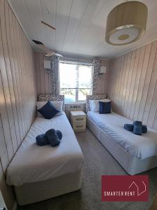 two beds in a small room with blue pillows at Milford on Sea - 4 Bedroom Lodge in Shorefield Country Park in Milford on Sea