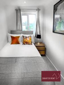 2 Bed House with Garden, Woking في Chobham: غرفة نوم بسرير ابيض مع مخدات ونافذة