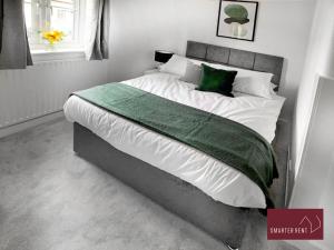een slaapkamer met een groot bed met witte lakens en groene kussens bij Vansittart Road, Windsor in Windsor