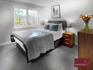 um quarto com uma cama grande e um vaso de flores em Maidenhead - Lovely Modern 3 bedroom house em Maidenhead