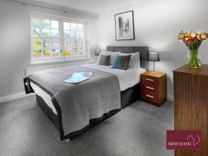 a bedroom with a large bed and a vase of flowers at Maidenhead - Lovely Modern 3 bedroom house in Maidenhead