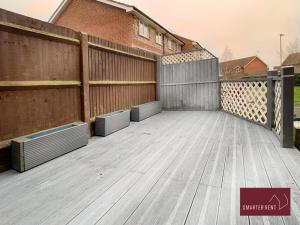 un patio trasero con una valla y una terraza de madera en Yateley - Spacious 2 Bedroom House, en Finchampstead