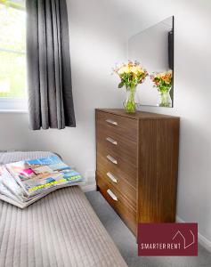 a bedroom with a dresser and a vase of flowers at Bracknell - Modern, Spacious 1 Bedroom House in Easthampstead