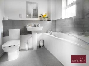 a bathroom with a white tub and a sink and a toilet at Bracknell - Modern, Spacious 1 Bedroom House in Easthampstead