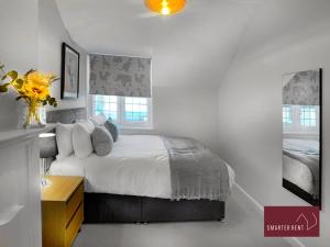 ein Schlafzimmer mit einem Bett, einer Kommode und zwei Fenstern in der Unterkunft Bray - Characterful 3 Bed House by the River in Bray