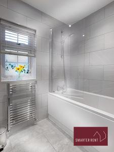 baño blanco con bañera y ventana en Wokingham - 2 Bed Modern House - Parking, en Wokingham
