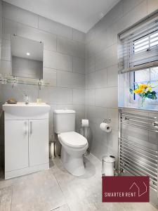 a bathroom with a white toilet and a sink at Wokingham - 2 Bed Modern House - Parking in Wokingham
