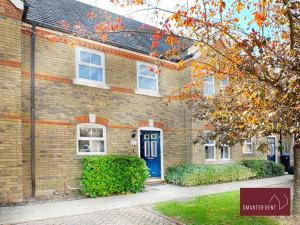 a brick house with a blue door in front of it at Knaphill - 2 Bedroom House - With Parking in Brookwood