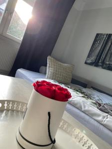 Gemütliche Wohnung in der Stadt 1 في آرنشتات: مزهرية بيضاء مليئة بالورود الحمراء على سرير