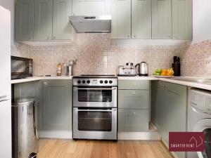 cocina con armarios blancos y horno de acero inoxidable en Wokingham - 2 Bedroom House, en Wokingham