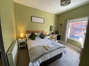 a bedroom with a bed with green walls and a window at Grosvenor Place Guest House in Chester