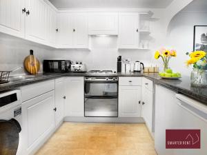a kitchen with white cabinets and a stove top oven at Hitchin - Millstream - 2 Bedroom Coach House in Ickleford
