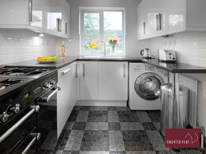 uma cozinha com armários brancos e uma máquina de lavar roupa em Farnborough - Peel Court - 2 Bed Parking & Garden em Cove