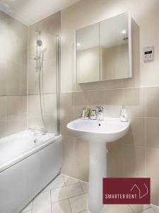 a bathroom with a sink and a mirror and a tub at Wokingham - 2 bed House with garden in Wokingham