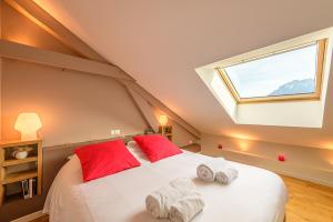 Un dormitorio con una cama grande con almohadas rojas y una ventana en La Villa suspendue, Jolie terrasse vue lac au calme - LLA Selections by Location lac Annecy, en Saint-Jorioz