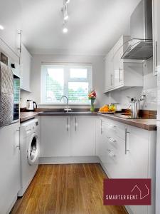 a white kitchen with a sink and a dishwasher at Lightwater - Immaculate 1 Bedroom House in Bagshot