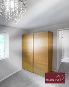 a room with a closet with a wooden door at Lightwater - Immaculate 1 Bedroom House in Bagshot