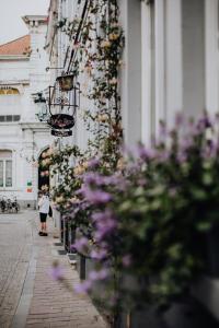 Una donna che cammina per una strada accanto a un palazzo con dei fiori di Hotel Rose Red a Bruges