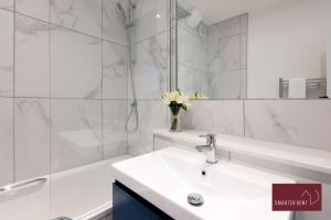 a white bathroom with a sink and a bath tub at Dorking - Brand New 1 Bedroom Apartment in Dorking