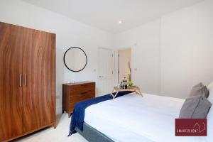 a bedroom with a large bed and a wooden cabinet at Dorking - Brand New 1 Bedroom Apartment in Dorking