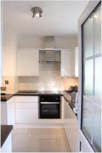 eine Küche mit weißen Schränken und einem schwarzen Gerät in der Unterkunft Wellesley, Central London Living in peaceful Suburb in Kenley