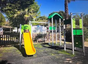 un parque infantil con tobogán amarillo en un parque en Mobil home 6 personnes en Saint-Cyprien