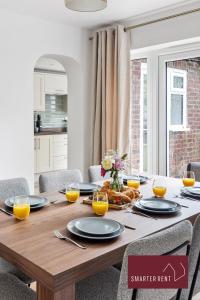 a dining room table with plates and glasses of orange juice at Woking - 4 Bedroom House - With Garden & Driveway in Brookwood