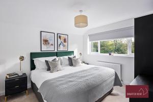 a bedroom with a large bed and a window at Woking - 4 Bedroom House - With Garden & Driveway in Brookwood
