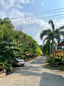 a car parked on a gravel road with palm trees at Baanrimklong bungalow in Ko Chang