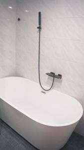 Mộc Phương hotel&massage في Kon Tum Kơ Nâm: حوض استحمام أبيض في حمام مع دش