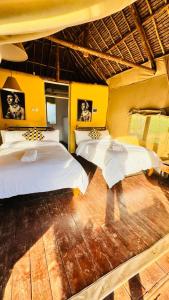 2 camas en una habitación con paredes amarillas en The Lookout, en Naivasha