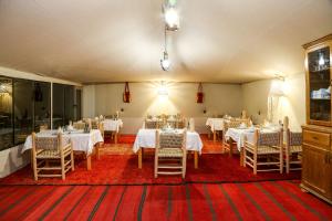 a dining room with white tables and chairs in it at Celia Desert Camp in Merzouga