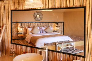 a bedroom with a large mirror above a bed at Celia Desert Camp in Merzouga