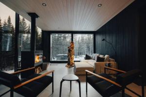 une femme est debout dans un salon avec une cheminée dans l'établissement Réflexion Charlevoix - Maisons Miroirs, à Petite-Rivière-Saint-François