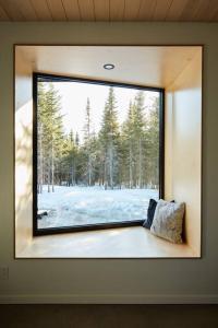 - une fenêtre dans une chambre avec vue sur la forêt dans l'établissement Réflexion Charlevoix - Maisons Miroirs, à Petite-Rivière-Saint-François