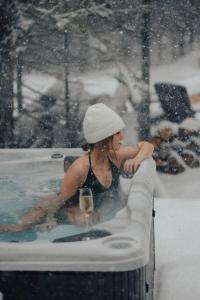 une femme assise dans un bain à remous dans la neige dans l'établissement Réflexion Charlevoix - Maisons Miroirs, à Petite-Rivière-Saint-François