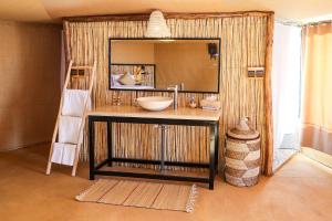 a bathroom with a sink and a large mirror at Celia Desert Camp in Merzouga