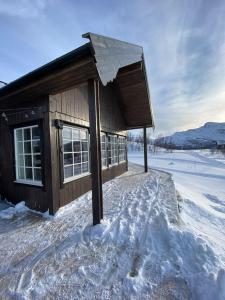 un piccolo edificio con neve per terra di Hytte i Neverfjord. a Kvalsund