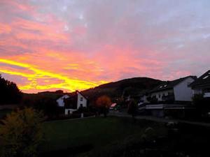 zachód słońca z czerwonym i żółtym niebem z domami w obiekcie Ferienwohnung Haus Weitblick w mieście Medebach