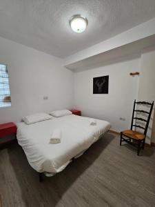 ein Schlafzimmer mit einem großen weißen Bett und einem Stuhl in der Unterkunft Agradable apartamento familiar in Sierra Nevada